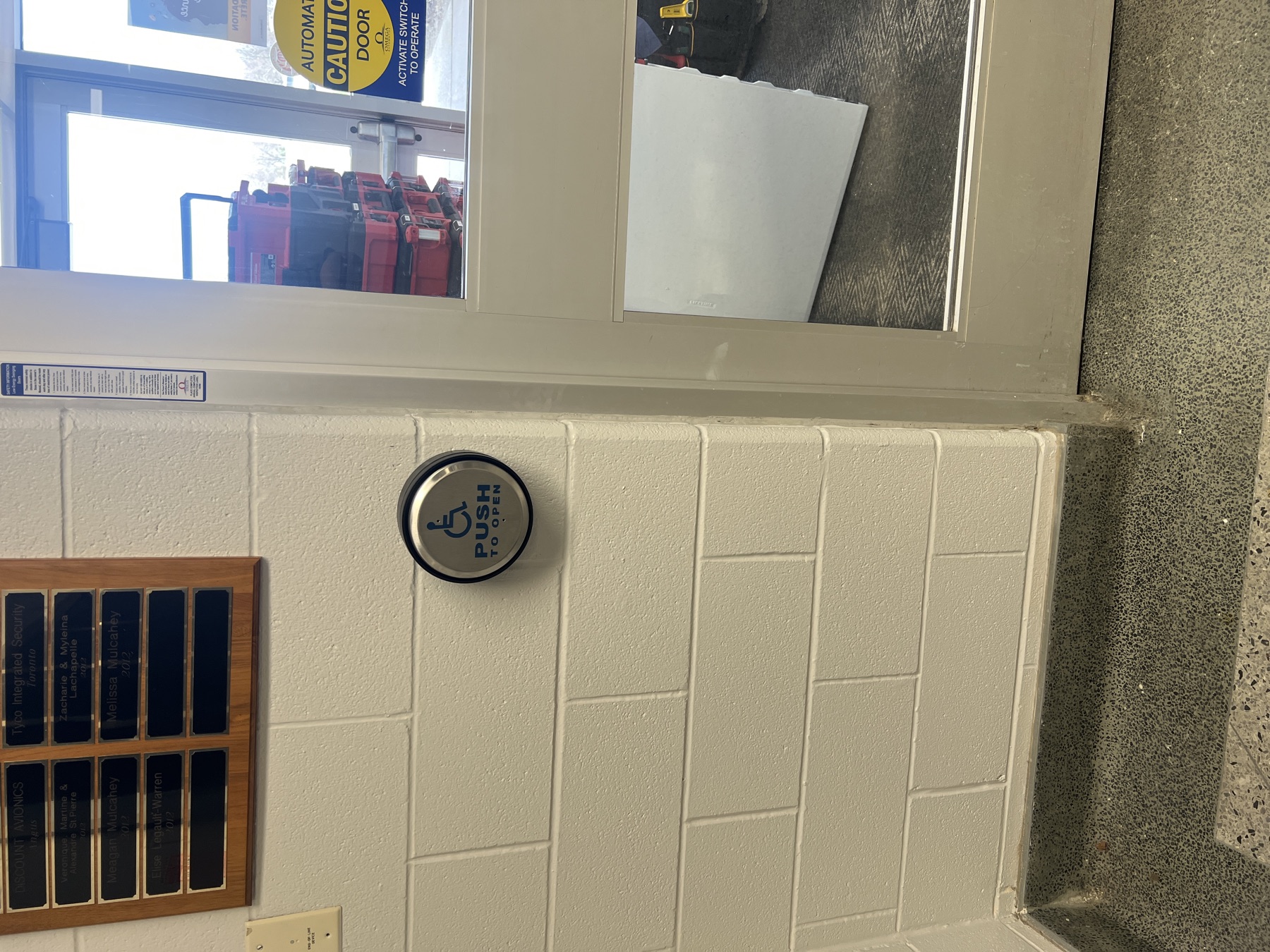 Accessibility push-to-open button beside a glass door.