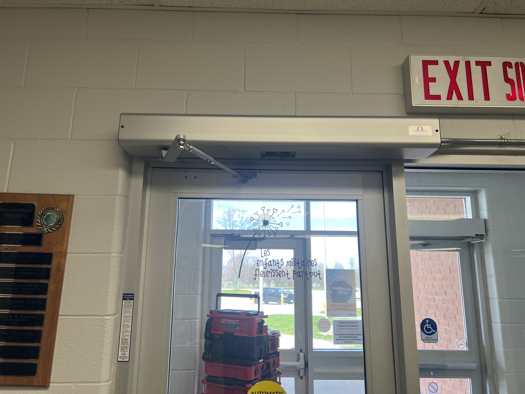 Automatic door operator mounted above a glass entrance.