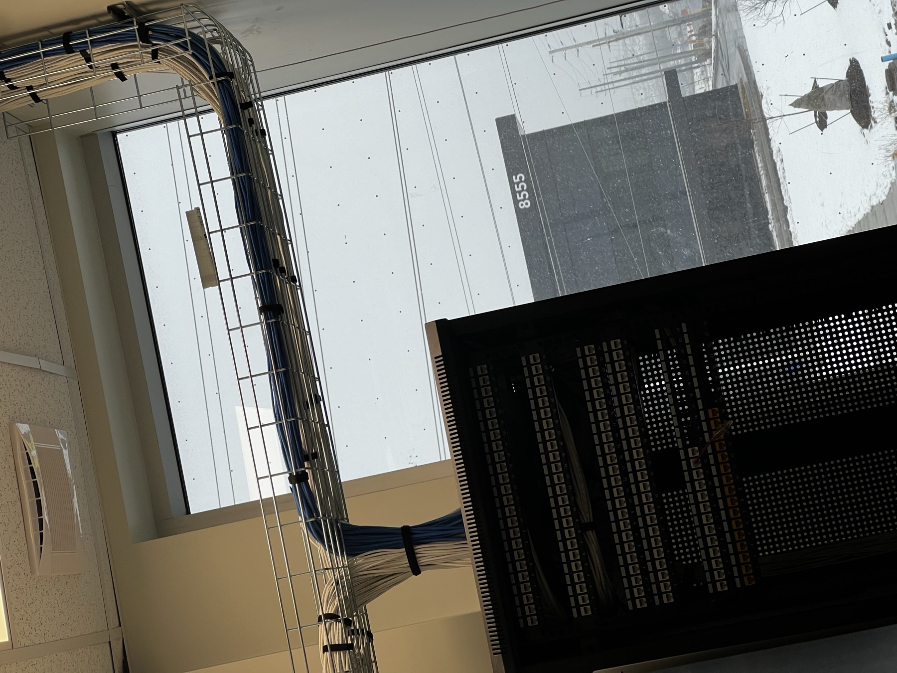 Cables dressed into a wire-basket tray at a window.