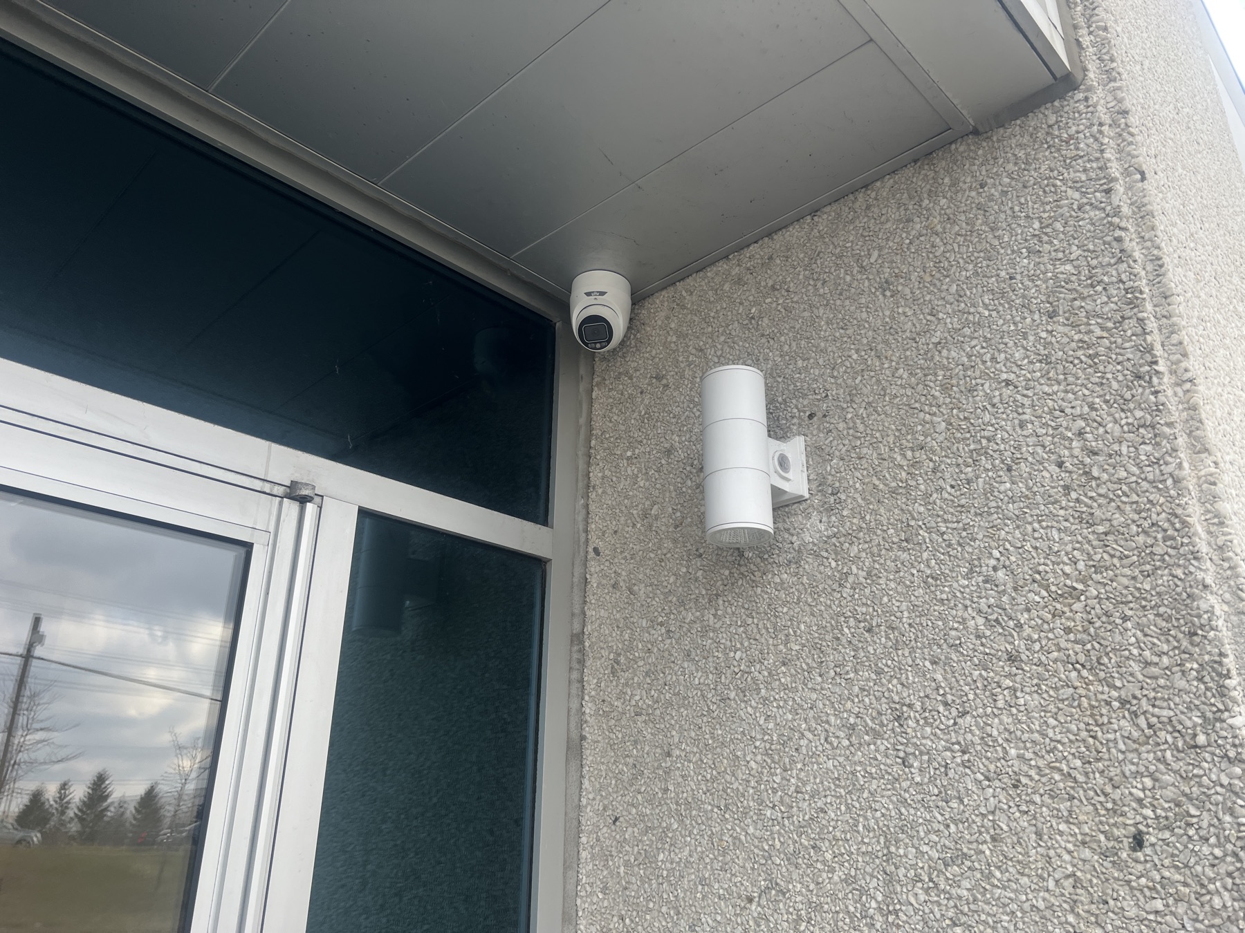 Dome camera on a soffit above a commercial glass entrance.