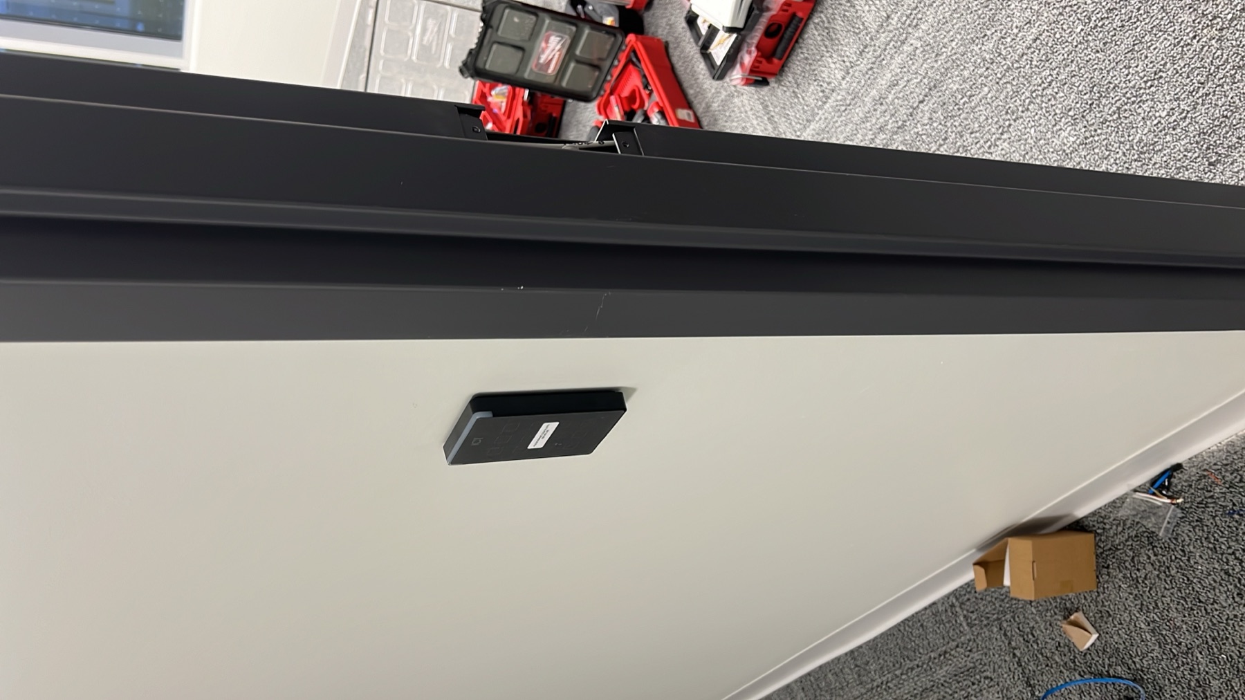 Card reader on a white wall beside a dark door frame.