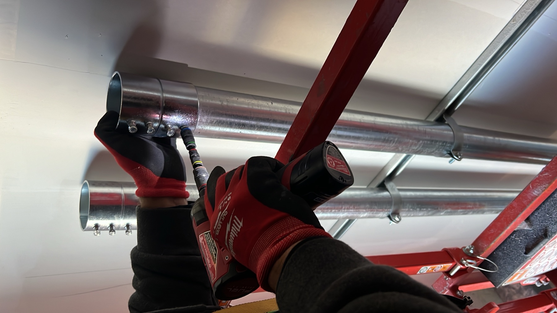 Conduit being secured to a wall from a lift platform.