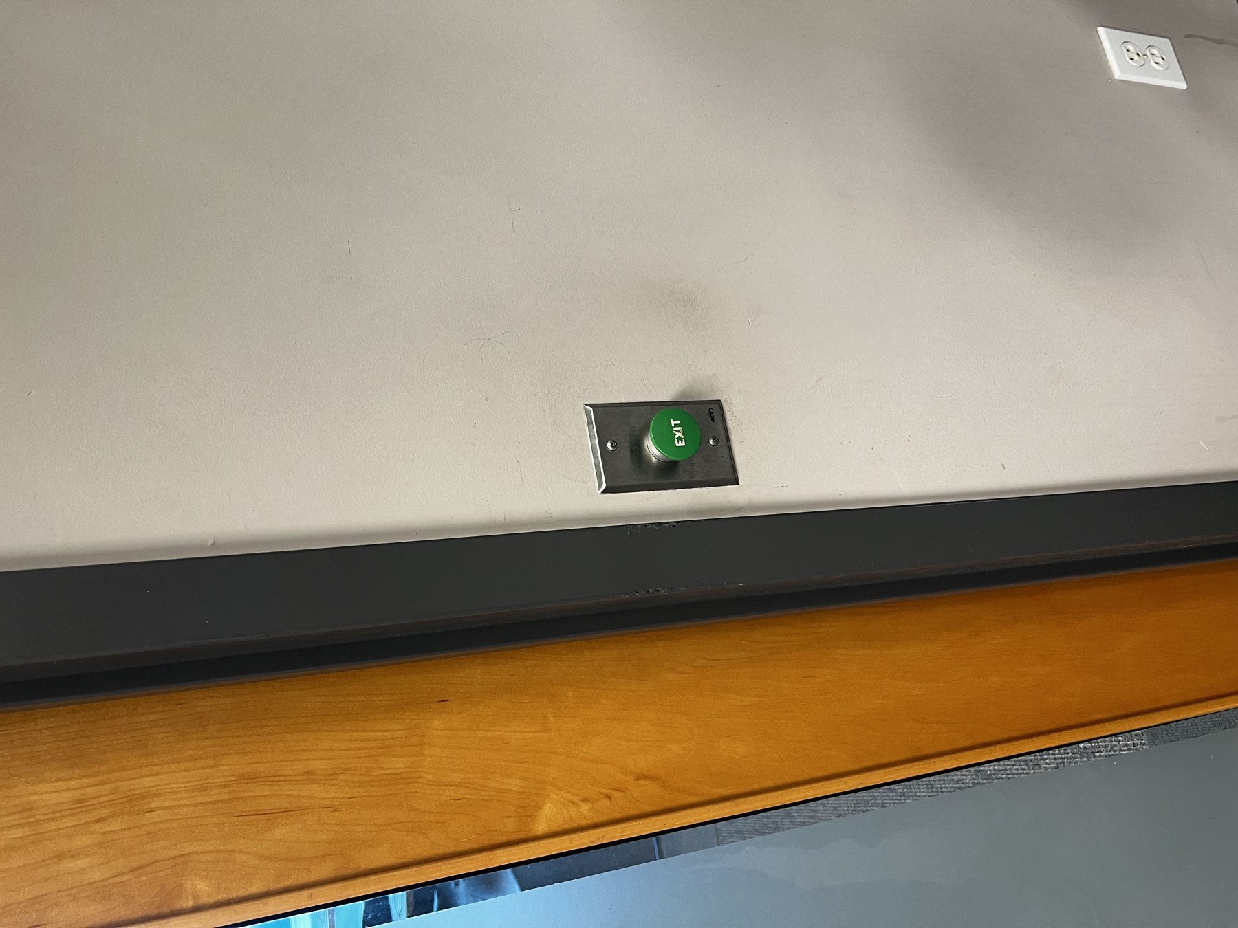 Request-to-exit push button beside a commercial door frame.