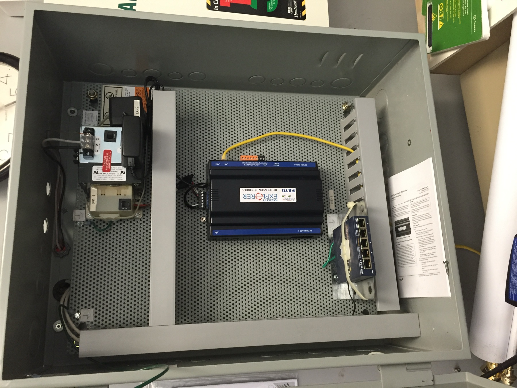 Open grey cabinet with a controller, switch, and dressed wiring.
