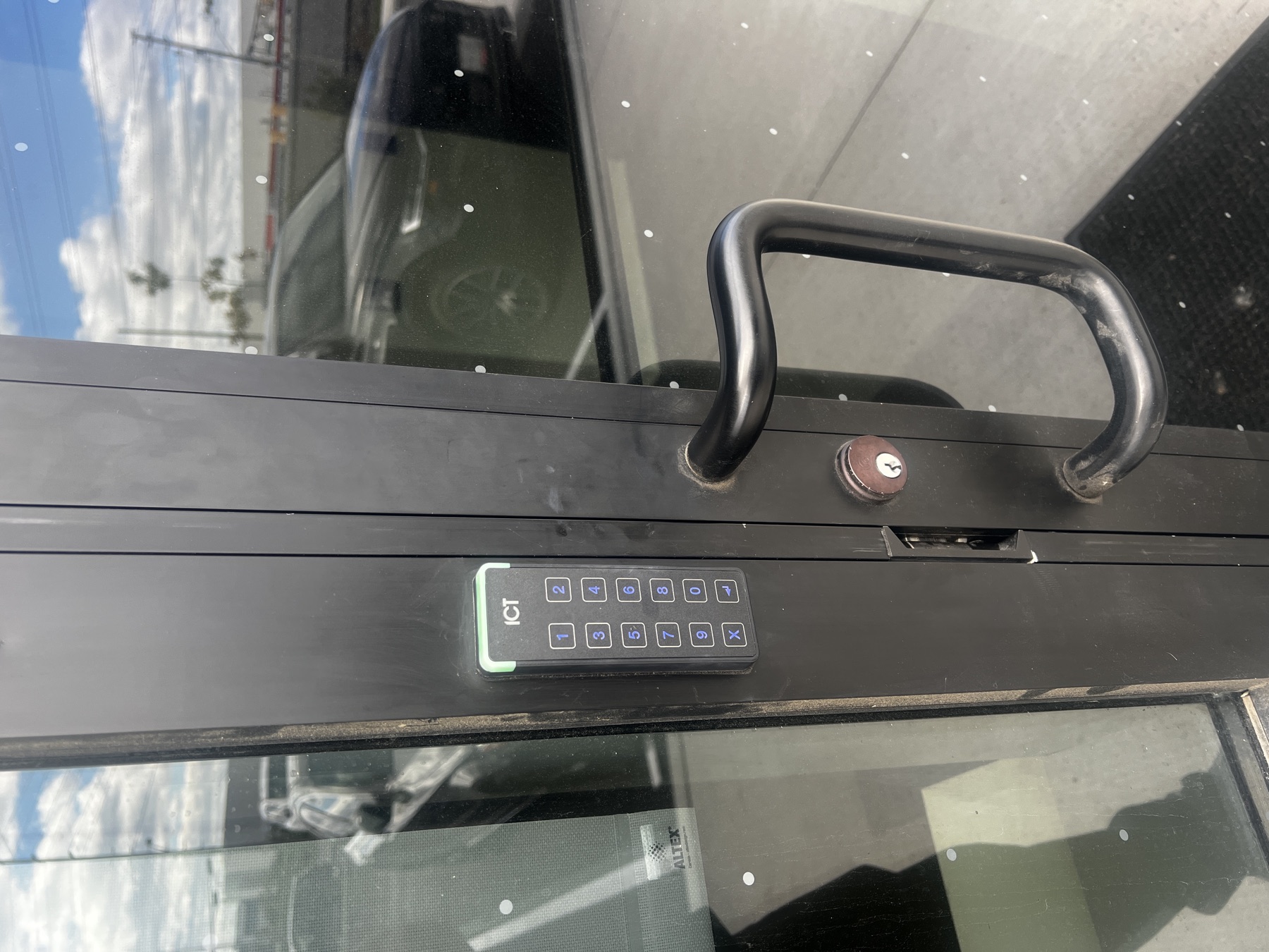 ICT keypad on a black-framed commercial glass door.