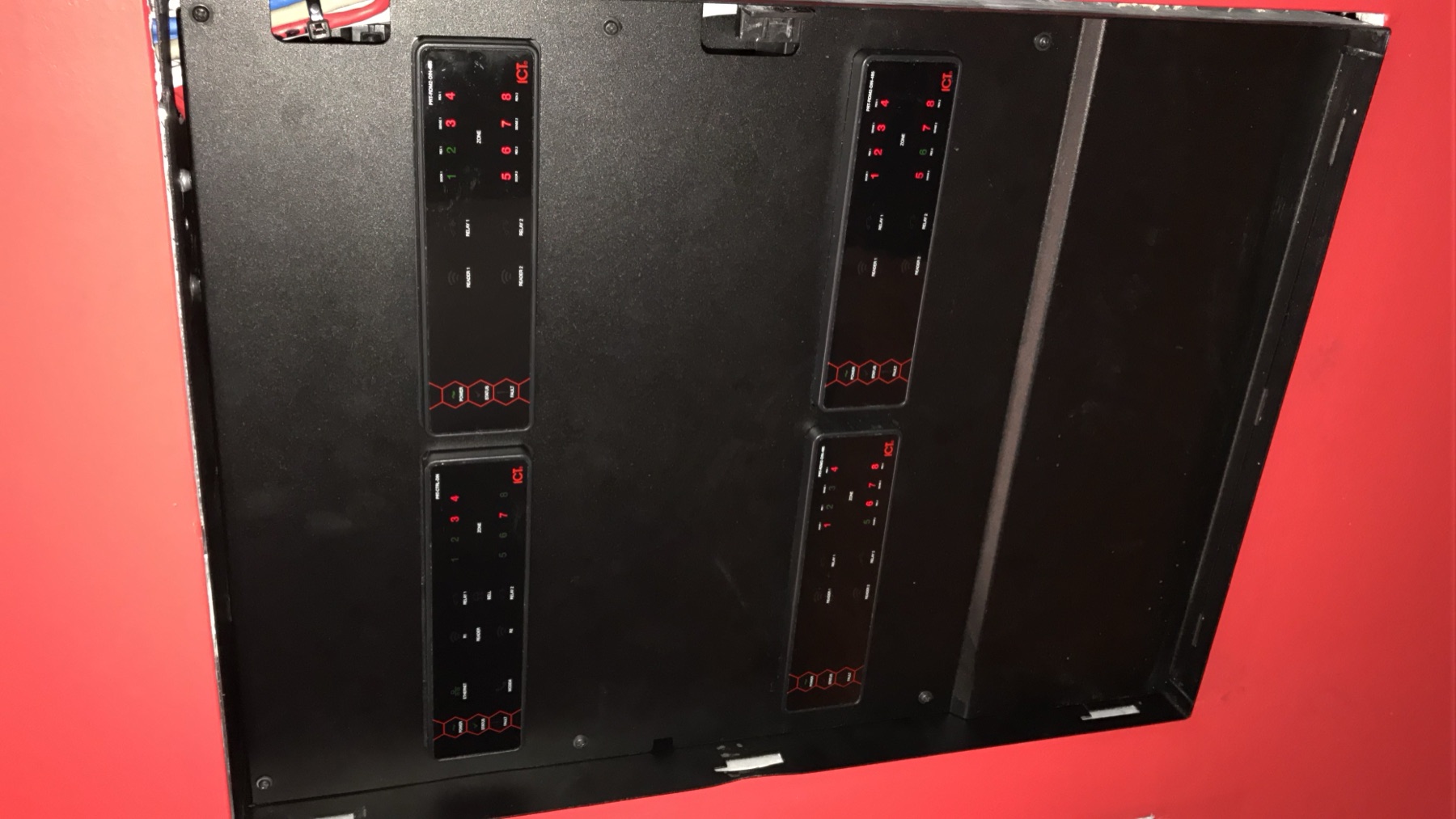 ICT controller modules in a black frame on a red wall.