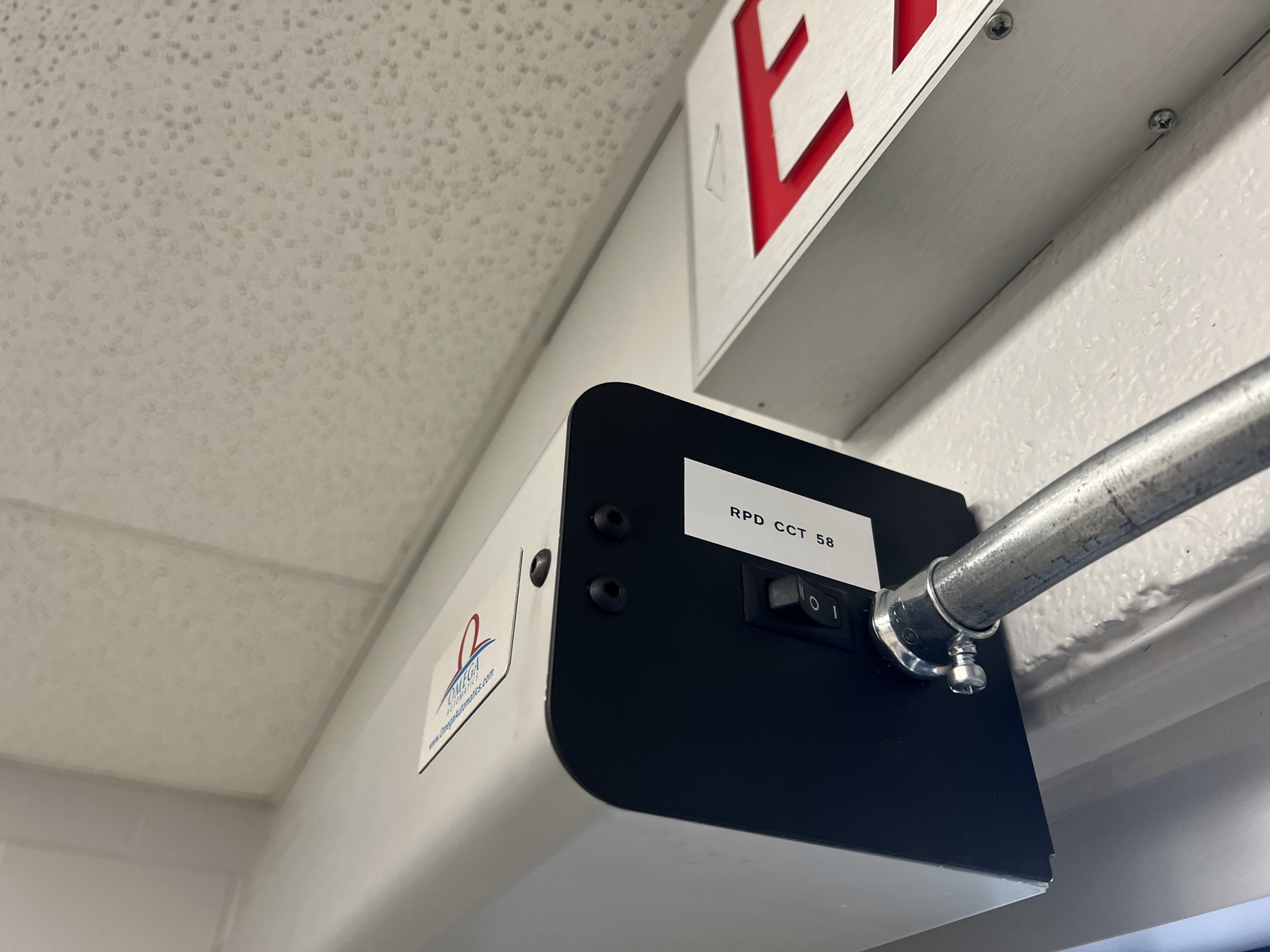 Door-operator housing with labelled switch and conduit.