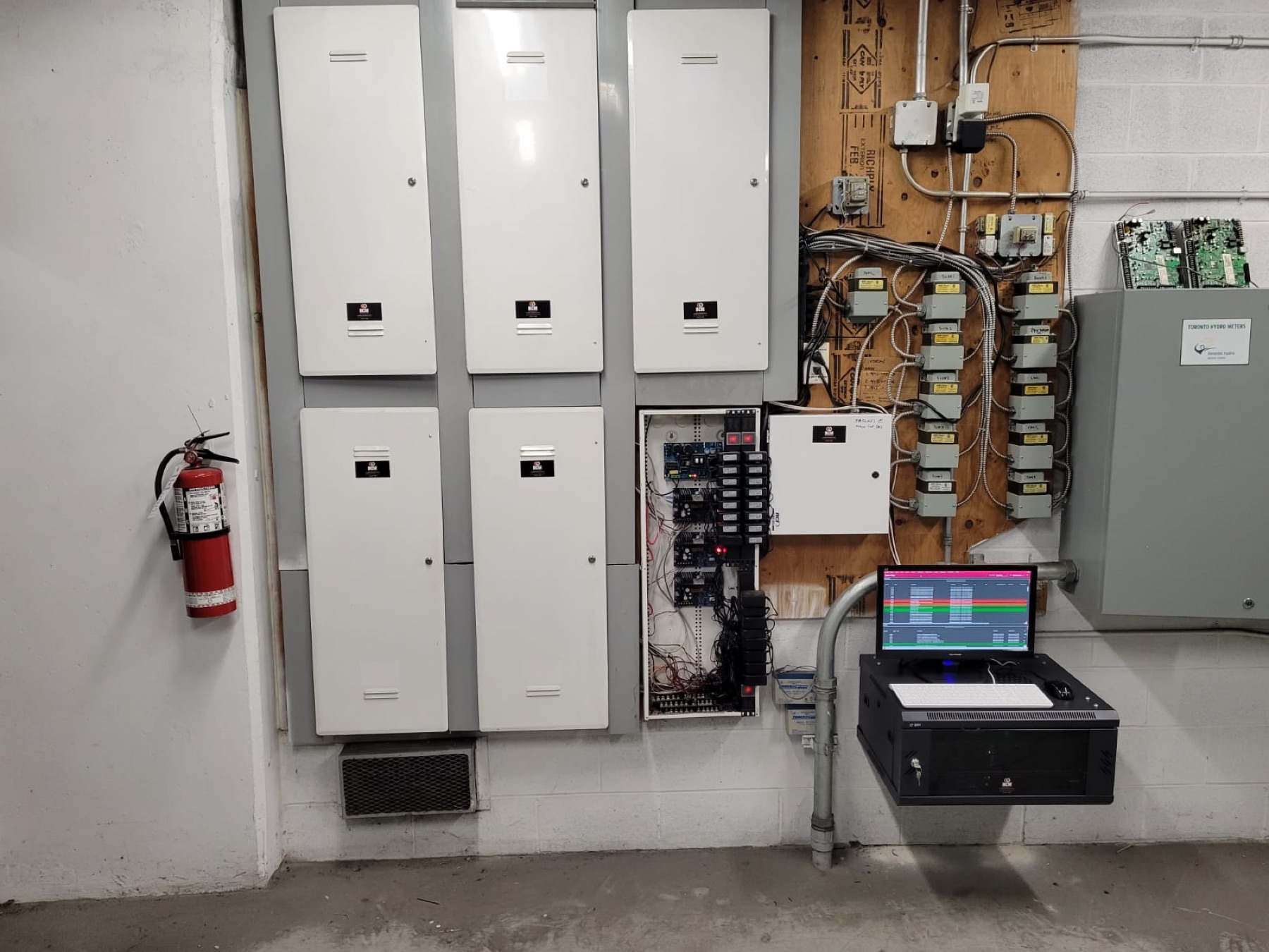 Grid of white control panels and transformers on a utility wall.