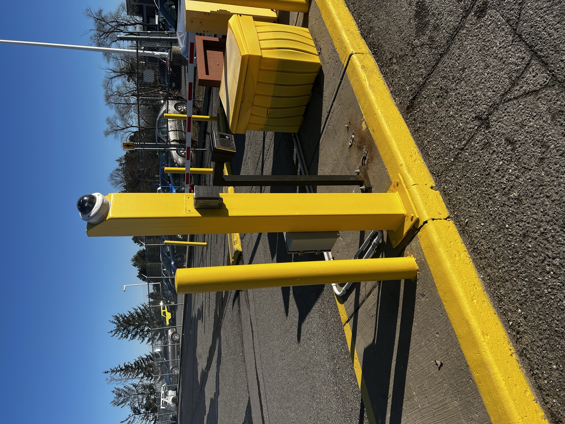 Gate pedestal with dome camera, keypad, and conduit.