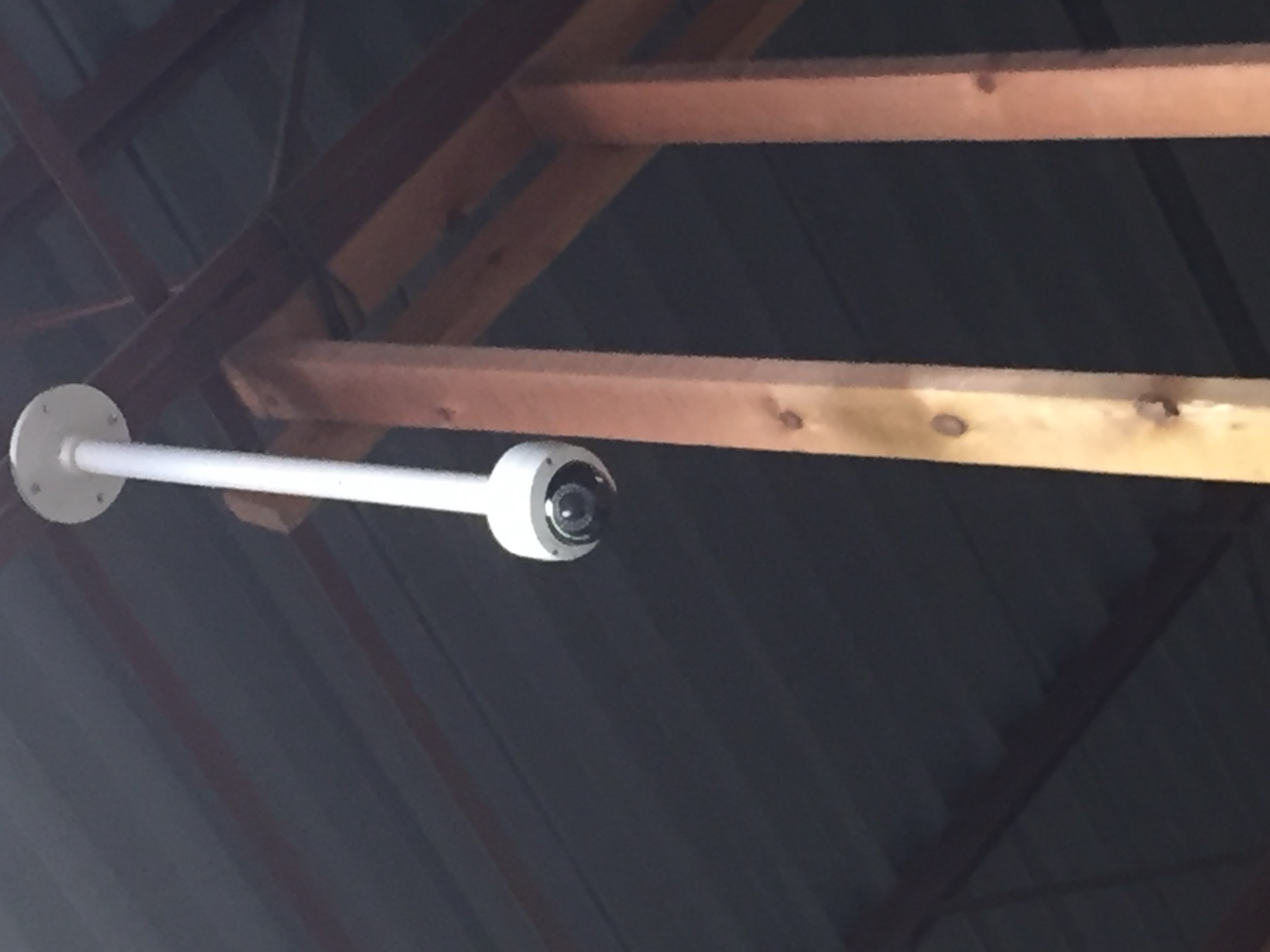 Pendant-mounted dome camera on a warehouse ceiling beam.