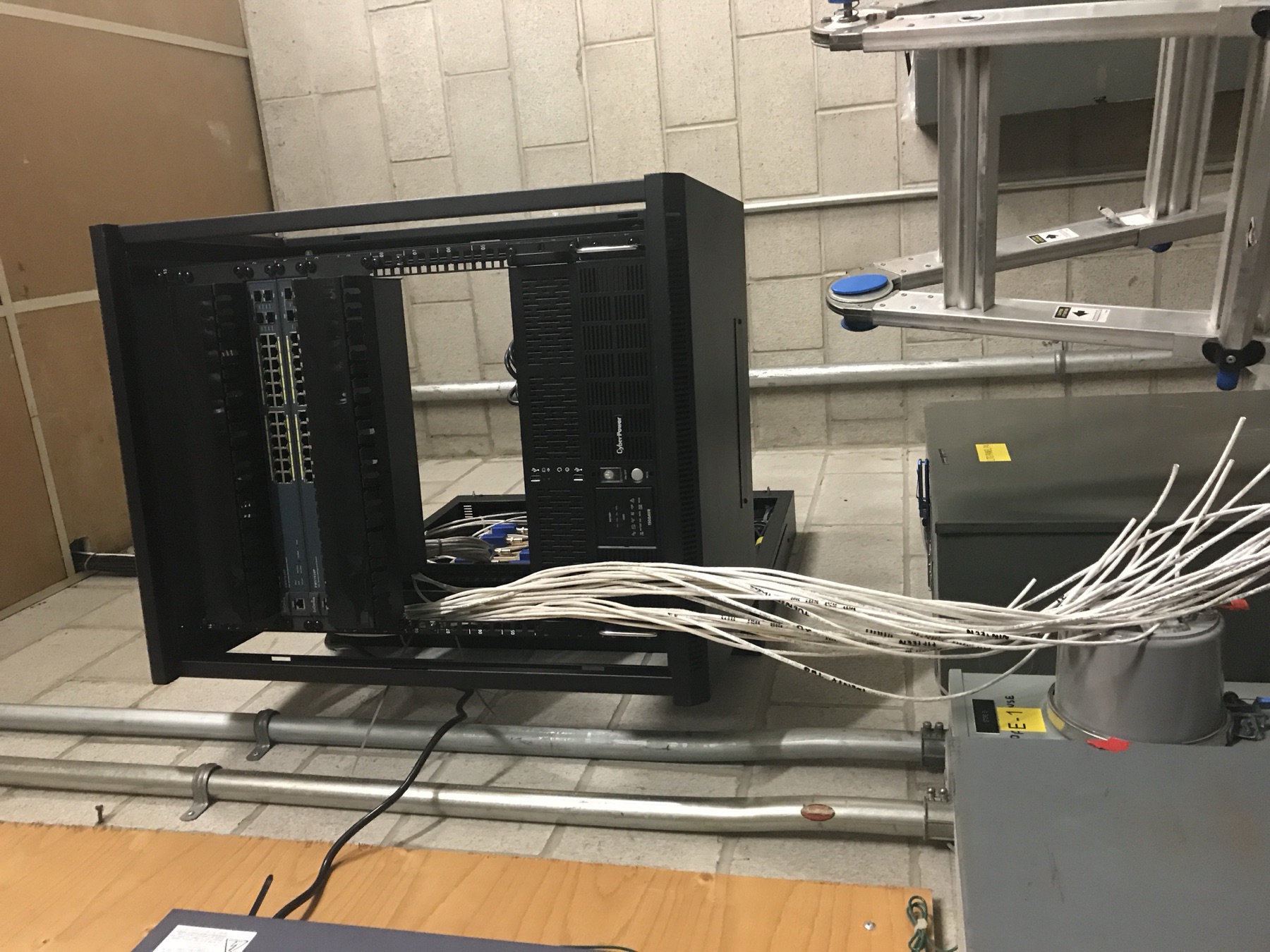Rack with a UPS and a white cable bundle being pulled.