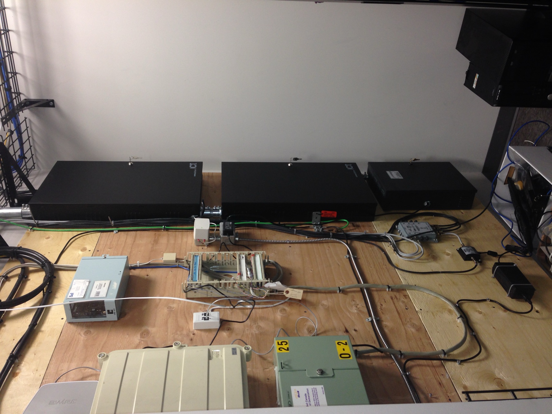 ICT cabinets and demarc equipment on a plywood telecom wall.