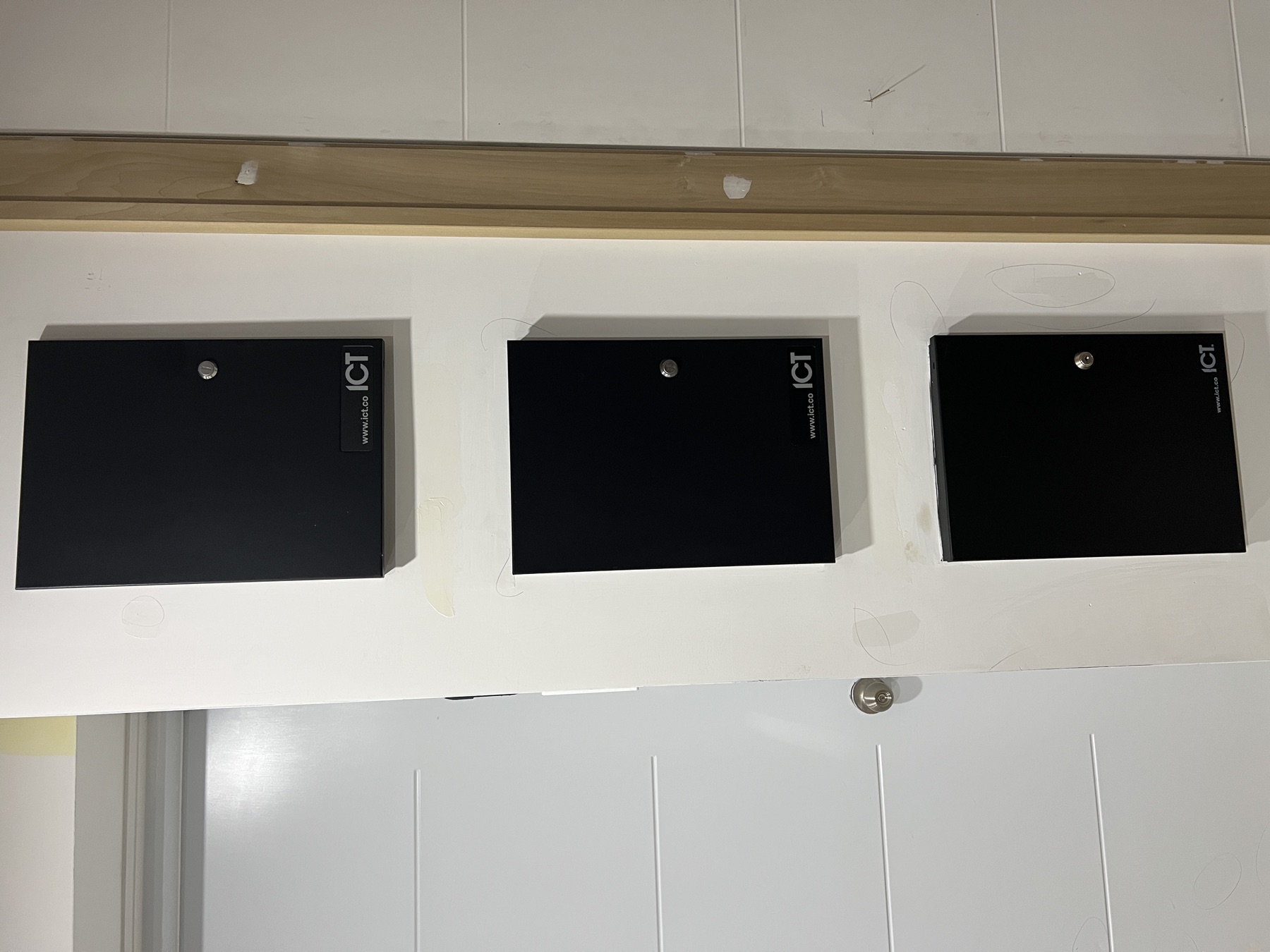 Three closed ICT enclosures in a row above a door.