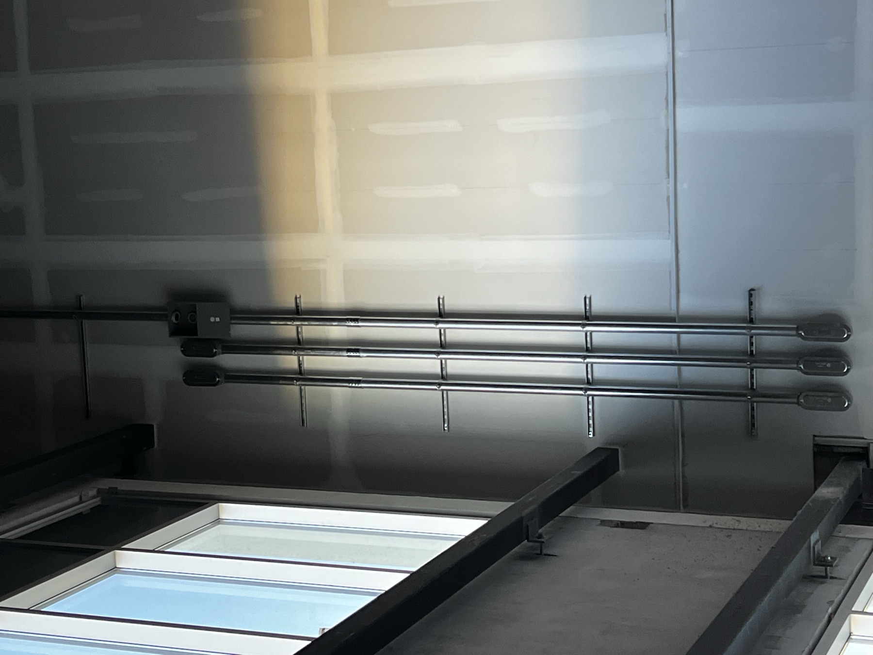 Vertical EMT conduit on strut along an unfinished commercial wall.
