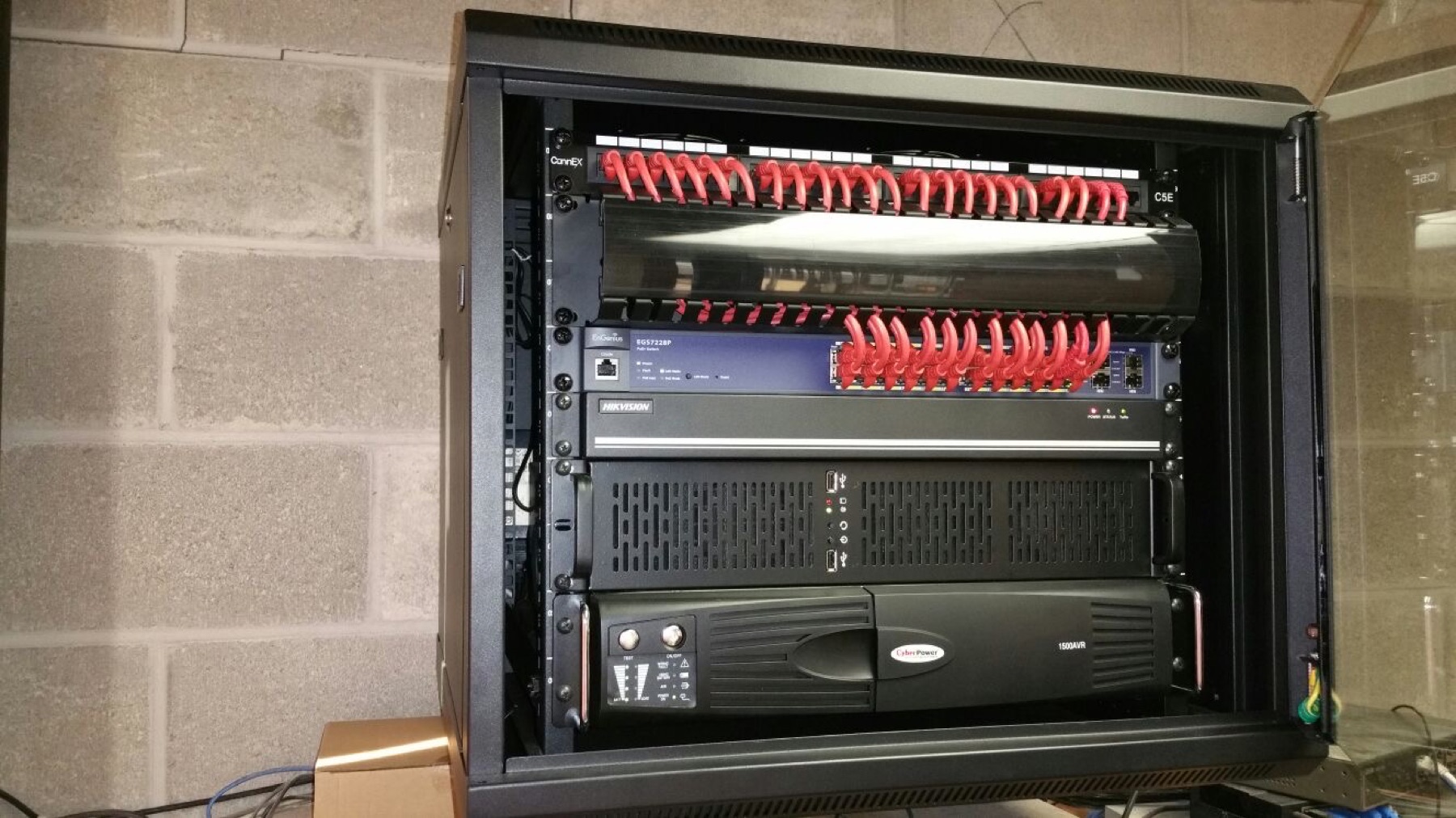 Wall-mount rack with patching, switch, recorder, and UPS.