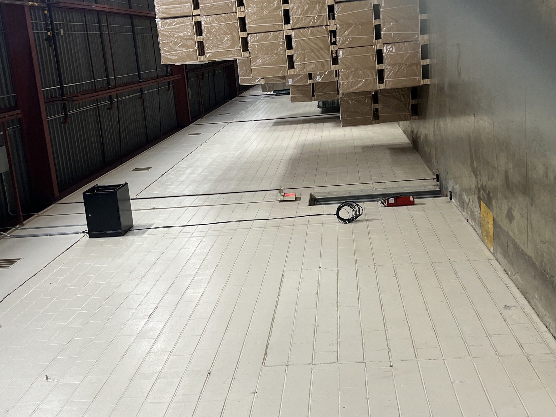 Black equipment cabinet on a raised warehouse floor.
