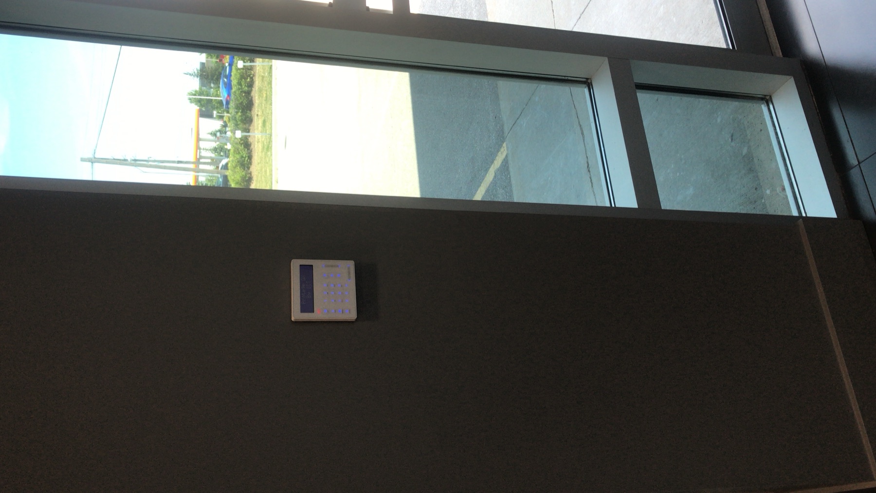 Wall keypad beside a glass entrance.