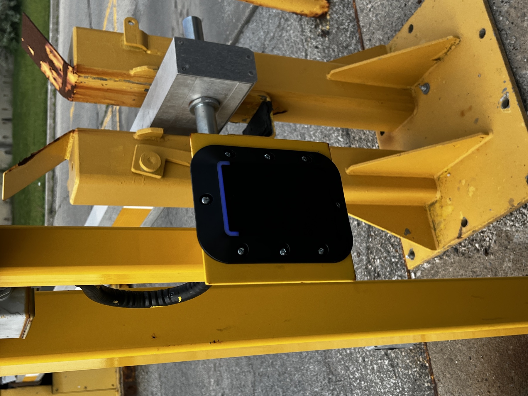 Card reader on a yellow steel gate post.
